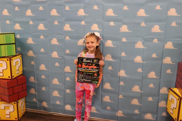 Kindergartener Olivia Wolford stands in the hallway with a first day of school sign on Aug. 1. Wolford will have Susan Mcewen as her teacher this year. (Photo/Anna Izquierdo)