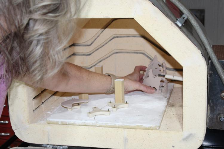 Tracy Massey sets one of her ceramic pieces into the kiln at her home in Arnoldsville, Georgia on  Aug. 28, 2025. Massey has one large kiln and one smaller kiln that she uses to fire all her pieces for her small business, Gallop and Glaze. (Photo/Emily Adams)
