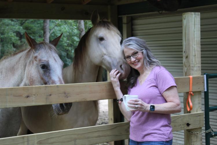 Tracy Massey smiles while hugging her horse Traveller at her home in Arnoldsville, Georgia, on Aug. 28, 2025. When creating her small business, Gallop and Glaze, Massey was inspired by her love for horses and used Snickers (left) as a model for the horse galloping in the Gallop and Glaze logo. (Photo/Emily Adams)