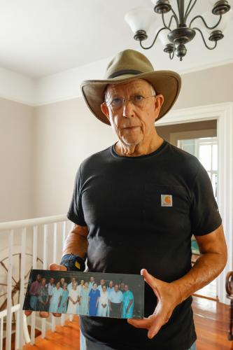 Chuck Brooks holds a photo of Hamilton McWhorter Jr. with family and friends during one of their “Supper Clubs” at his home in Lexington on Aug. 28. Brooks grew up around McWhorter, a close friend of the Brooks family, and he often attended Georgia football games with them. (Photo/Susanna Johnson)