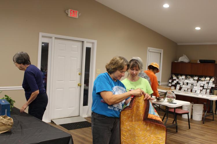 Vickie Coker (right) and another Plowshare member look at a quilt during the raffle at their 11th anniversary meeting on Monday, Sept. 6, 2025, at the Georgia Farm Bureau in Crawford. The meeting included a potluck, a presentation by Geoff Hill on pawpaws, and a raffle. (Makenna Reavis/The Oglethorpe Echo)