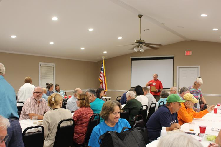 Plowshare members wait to hear their number as Steven Coker calls out winning raffle tickets at their 11th anniversary meeting on Monday, Sept. 6, 2025, at the Georgia Farm Bureau in Crawford. Members bring in items to raffle off and get to pick from the table of items when their number is called. (Makenna Reavis/The Oglethorpe Echo)