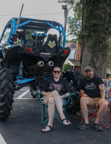Brandon and Alicia Yarbrough of Stephens sit in folding chairs next to their 2017 Can-Am Maverick 1000R side-by-side off-road vehicle at the Firefly Cruise-In in Lexington, Georgia on Sunday, Sept. 28, 2025. The couple is set to take their UTV down to Florida soon to participate in a yearly off-road vehicle convention. "Some people go to the beach — we go play in the mud," Brandon Yarbrough said. (Photo/Susanna Johnson)