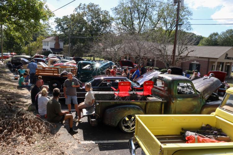 In the mid-afternoon sun, attendees and vehicle owners sip beverages and converse with friends at the Firefly Cruise-In in Lexington, Georgia on Sept. 28, 2025. The cruise-in lasted four hours, giving attendees plenty of time to browse the vintage vehicles, get a snack and chat with friends. (Photo/Susanna Johnson)