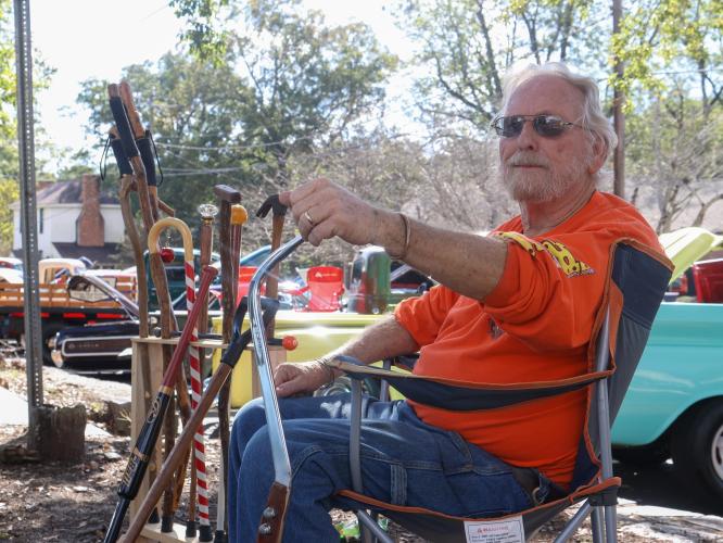 David Lowe sits in a lawn chair next to a collection of his handmade walking sticks at the Firefly Cruise In in Lexington, Georgia on Sept. 28, 2025. In addition to his love for vintage cars, Lowe enjoys making and selling walking sticks from unique items like hammers and shovels. (Photo/Susanna Johnson)