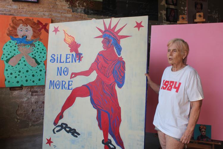 Kristan Ryan, owner of ArtGirl's Out Loud Art Gallery in Lexington, explains the story behind one of her pieces on display. Though much of her work is political, Ryan said her art advocates for suffering men, women and children. (Hannah Freeman/The Oglethorpe Echo)