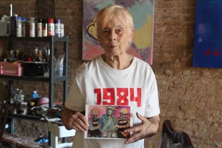 Kristan Ryan holds a postcard print of her painting. Ryan said she started selling prints so her art could be more accessible to people who couldn't afford her full pieces. (Hannah Freeman/The Oglethorpe Echo)
