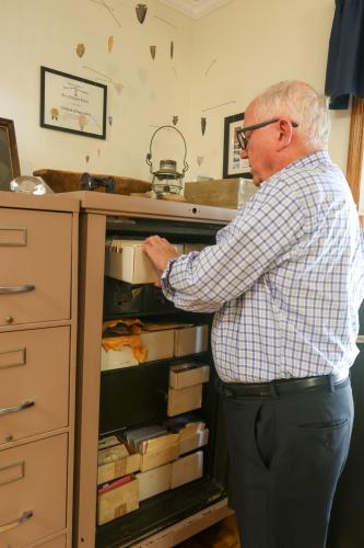 Gary Doster takes a box of postcards out of a cabinet at his home in Athens last week. He said he's read the message on every card in his posession. (Photo/Susanna Johnson)