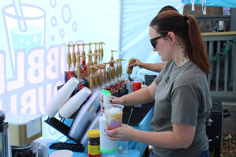 Jamie Ovinnio, creator of small business Bubble Trouble, makes a “dirty soda” for herself at the Christmas Marketplace on Sunday at the Crawford Depot. It was Bubble Trouble’s first time participating in the event. “We’re (the vendors) always introducing each other — we pass around business cards if we don’t know each other, if it’s a new vendor,” Ovinnio said. “It’s really great because the other vendors are coming together as a small town and working together, and I really like that.” (Photo/Emily Adams)