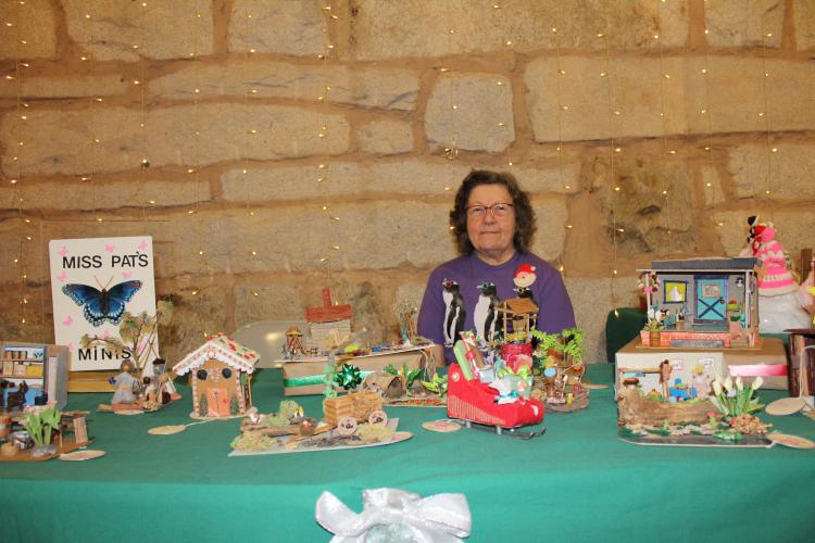 Miss Pat’s Mini’s is 80-year-old retiree Pat Taylor’s booth that sells a handmade variety of miniature scenes at the Christmas Marketplace at the Crawford Depot on Sunday. Taylor has been making the scenes for about two years as a hobby and finds many of the materials in her yard. (Photo/Emily Adams)