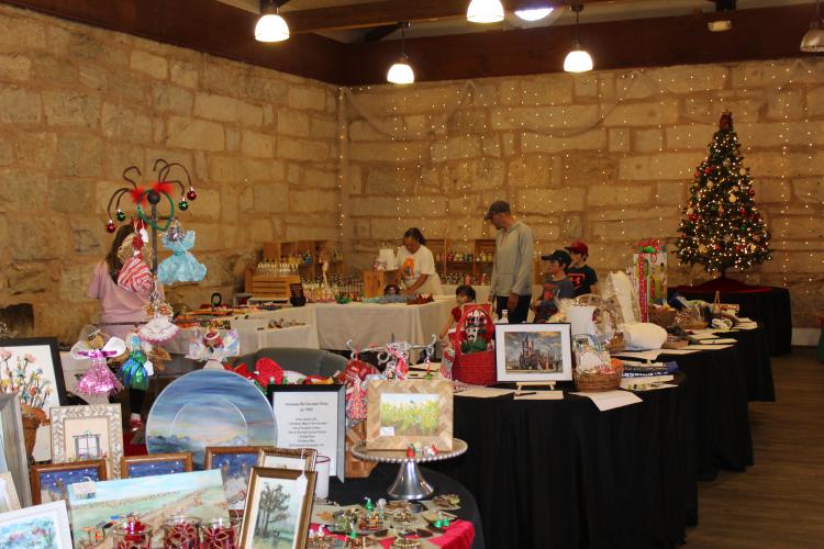 The interior of the Crawford Depot hosts vendor booths and silent auction tables for the annual Christmas Marketplace on Sunday. The market offered shoppers handmade holiday goods while providing exposure for many small businesses. “I love creating what my plan is in my head, making the dreams come true, and really making it as colorful or as exciting as I want it to be,” said Jamie Ovinnio, owner of the small business and marketplace vendor Bubble Trouble. (Photo/Emily Adams)