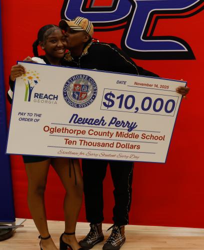 Nevaeh Perry receives a cheek kiss from her aunt while holding her REACH Georgia Scholarship check on Friday, Nov. 14, 2025. The family celebrated her accomplishment with pride, cheering her on as she begins planning for college. (Photo / Drew Bearden)