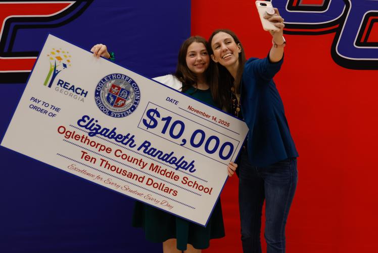 Elizabeth Randolph smiles as her mother takes a selfie with her and the $10,000 REACH Georgia Scholarship check on Friday, Nov. 14, 2025. Randolph said the moment feels “kind of surreal” and hopes to study microbiology at the University of Georgia. (Photo / Drew Bearden)
