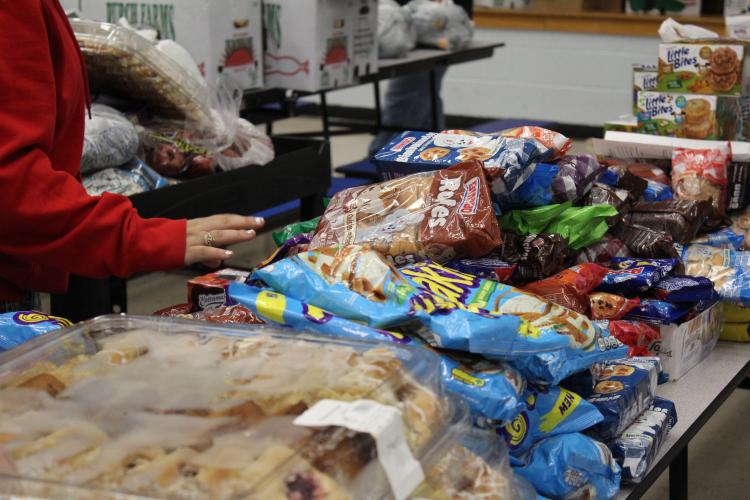 A family selects items from the dry goods table at the OCHS food pantry on Nov. 20. Jodie Zeuke, a parent mentor at OCHS, said the pantry is organized like a grocery store so families are able to take the items they want and need. (Hannah Freeman/The Oglethorpe Echo)