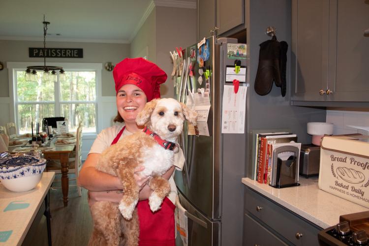 Izzy Marler, CEO of Three Dogs and a Girl Bakery, poses with Axel, the 6-year-old goldendoodle and service dog. The bakery is run inside the Marler family’s Winterville home. (Grace Burnett/The Oglethorpe Echo)