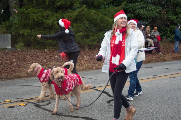 Jerri Lynn Gabriel, Rhonda Mathis and Penni Stoudenmire walk through the parade and pass out candy with their goldendoodles. The entire crew are wearing festive Christmas sweaters. (Grace Burnett/ The Oglethorpe Echo)