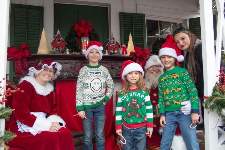 The Archer family smiles with Santa Claus and Mrs. Claus after the Christmas parade while wearing festive sweaters. Santa stayed after the parade to mingle with families. (Grace Burnett/The Oglethorpe Echo)