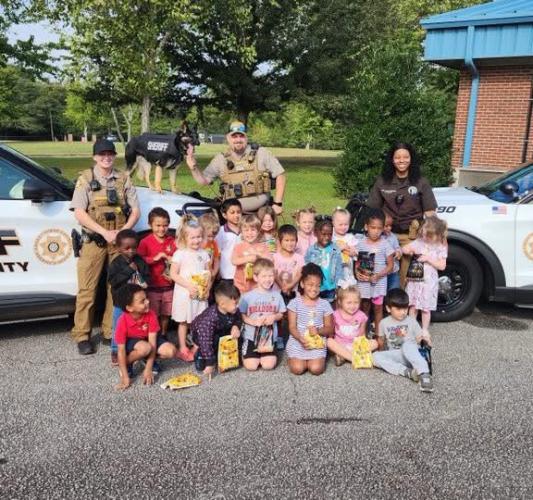 Deputy Courtney Corbin (left), K-9 Roni, Sgt. AJ Wiles (center) and Deputy Karshiuania Rucker (right) gather with Oglethorpe County Elementary School students at a Community Helper Day on Sept. 17. Roni drew attention from students who learned about the role of police dogs in keeping their community safe. (Submitted Photo)
