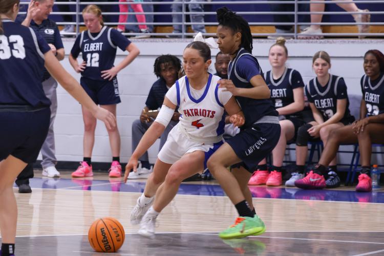 Oglethorpe County senior Elin Turner dribbles the ball past Elbert County player Justis Banks on Feb. 10. The Patriots lost to the Blue Devils with a score of 40-58. (Photo/Addison Simmons)