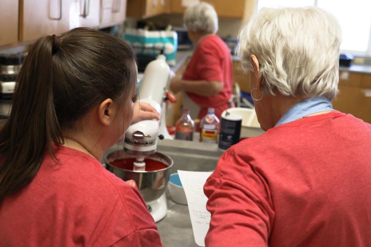 Jill Kort and Jennie Sturgis look over a recipe while prepping cupcake batter for the CAYA House's annual Valentine's Day fundraiser on Friday, Feb. 13, 2026, in Lexington, Georgia. The group of nine volunteers had to make enough batter for over 3,000 cupcakes. (Photo/Sydney Shankman)