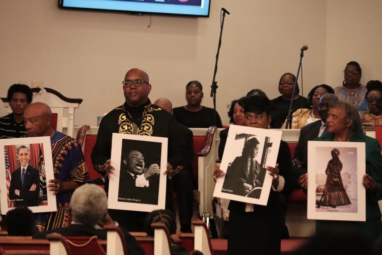 Representatives from New Bethlehem Baptist Church hold pictures of notable Black figures during the Black History Collaborative at Thankful Baptist Church in Stephens on Sunday. Several churches came together for the celebration. (Photo/ Mia Tanner)