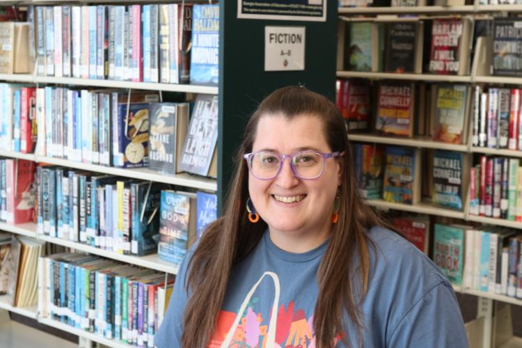 Oglethorpe County Library manager Nicole Hensley stands by a bookshelf at the Oglethorpe County Library. Hensley said the library relies heavily on social media. Using different features on Facebook has helped pass information on throughout Oglethorpe County. (Photo/Riley Baugh)