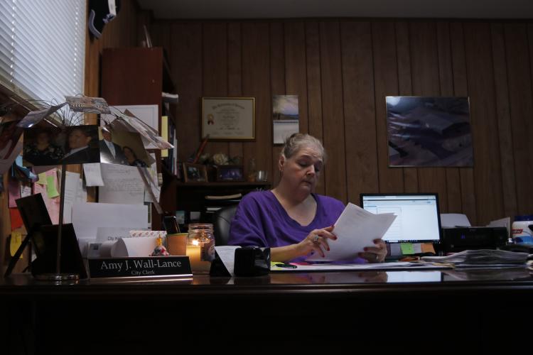 Crawford City Clerk Amy Wall-Lance reads through documents at her desk Friday, March 6, 2026, inside Crawford City Hall. Wall-Lance has worked for the city for nearly three decades. (Photo/Riley Baugh)