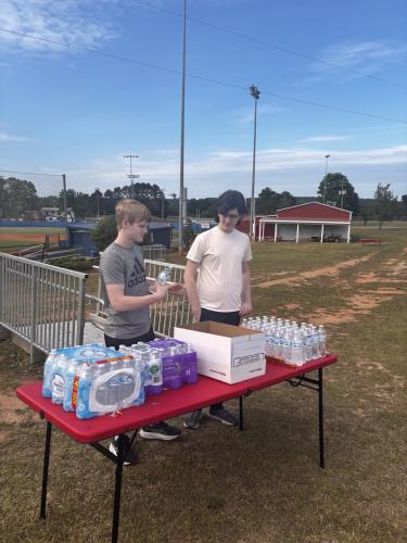 Ethan Wilson and Eli Austin, sophomores and members of the National Honor Society at OCHS, pass out water bottles and snacks at the OCHS National Honor Society Color Fun Run. “Having fun, setting up stuff, just being with my friends talking about it, it’s pretty fun,” Wilson said. (CHARLOTTE COCHRAN/THE OGLETHORPE ECHO)