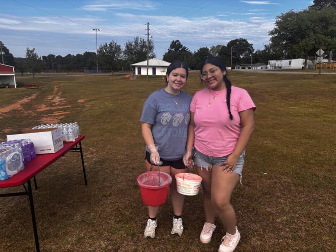 Khalissa Holland and Yadhira Moreno, sophomores and members of the National Honor Society at OCHS, volunteer by tossing the colored powder at the OCHS National Honor Society Color Fun Run, on April 25, 2026. “It’s very fun, having to do our volunteer hours and trying something new,” Moreno said. (CHARLOTTE COCHRAN/ THE OGLETHORPE ECHO)