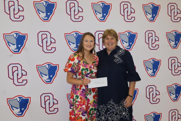 Andee Dellinger (left) holds her check for $1,000 as the first recipient of the Beverley Levine Patriot Pride Scholarship, in honor of Superintendent Beverley Levine (right), who is retiring this year. The scholarship was a surprise for Levine. (Ellie English/The Oglethorpe Echo)
