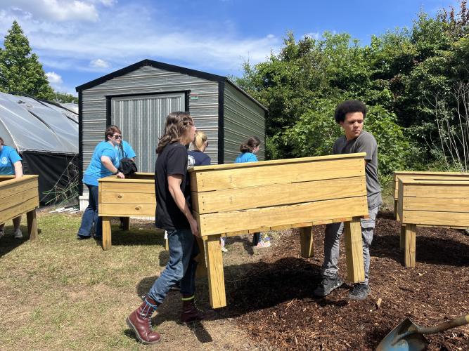 Mason Drewett, left, and Aydin Aziz carry one of the raised garden boxes into a newly mulched garden area on Tuesday at the Oglethorpe County Senior Center. (Photo/Emilie Sullivan)