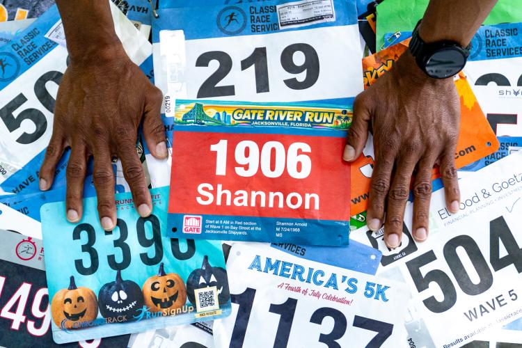Arnold places his collection of running bibs on a table in Maxeys. “I want to get all of them and put them in a room,” Arnold said. (Ethan Greene/ The Oglethorpe Echo)