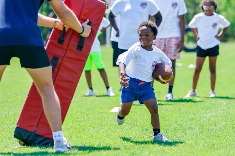 A camper runs around an obstacle as part of a drill during the Bonds Movement Youth Football Camp on Saturday at Oglethorpe County High School. Bonds said he often has older kids show younger ones how to do such drills. "It’s teaching those older kids how to become leaders on the football field," Bonds said. (Ethan Greene/The Oglethorpe Echo)