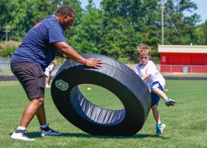 KB Bonds, organizer of the Bonds Movement Youth Football Camp, works through a drill with a camper on Saturday at the OCHS football field. In its second year, the free event drew 60 kids, ages 5 to 16, to the camp. (Ethan Greene/The Oglethorpe Echo)