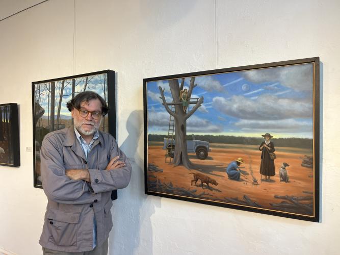 Lexington resident Terry Rowlett stands next to a painting featured in his exhibit, Before the End of Time, at the Oconee Cultural Arts Foundation in Watkinsville. The red clay landscape in the painting is representative of Georgia, he said. (Sarah Nanos/The Oglethorpe Echo)