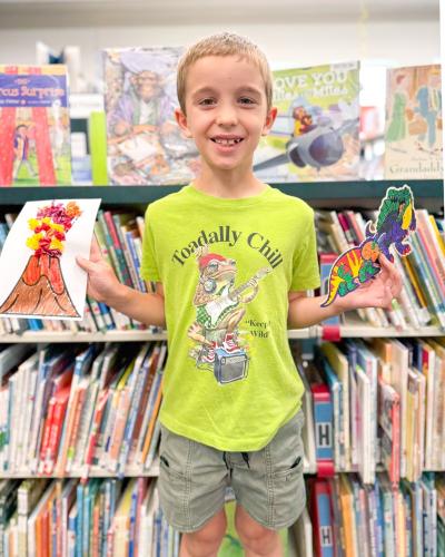 Rylan Adams shows off his artwork at The Oglethorpe County Library. Throughout the summer, the library has been hosting events organized around the summer theme "Unearth a Story," with a focus on science, local history and dinosaurs. (Submitted Photo)