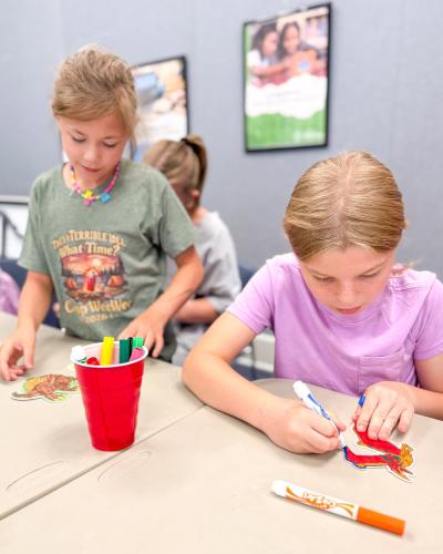 Kennedy McNair (left) and Callie Adams work on their dinosaur artwork at the Oglethorpe County Library. As a part of the summer reading program, the library hosts events throughout the summer, ranging from scavenger hunts and line dancing to crafts and story time. (Submitted Photo)