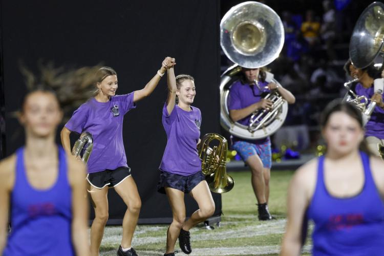 Rylee Stanley (left) and Cailyn Torbit run onto the field holding hands for the Oglethorpe County High School marching band performance at halftime of the game against Washington-Wilkes on Sept. 4. Stanley also plays for the softball team. (Photo/Zachary Krausman)