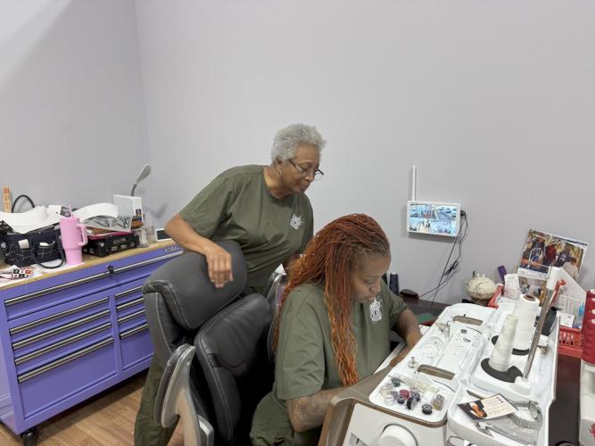 Henrietta (Nell) Browne stands over her daughter Nicole Browne at Altered Ego, their sewing shop in downtown Comer. The store officially opened on Aug. 28. (Photo/Ren Grimsley)