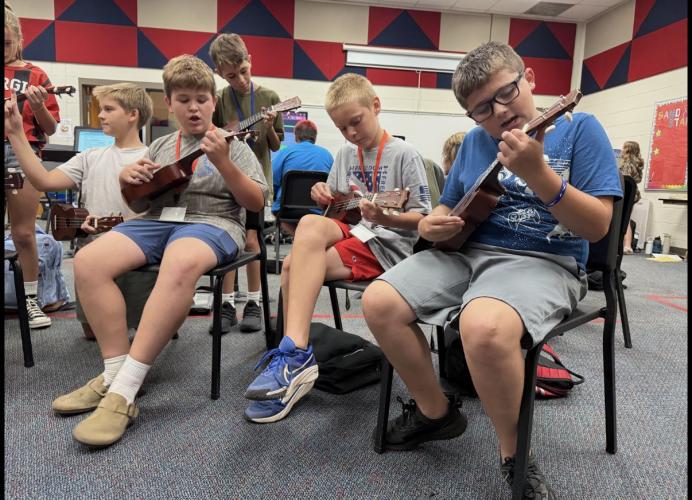 Left to right: Hunter Taft, Roman Allen, Tucker Baker, Jax Sims and Wyatt Fabrizio gather around to play a ukulele version of "Let It Be" by The Beatles. The students learn songs in the key of C (Photo/Walker Durham).