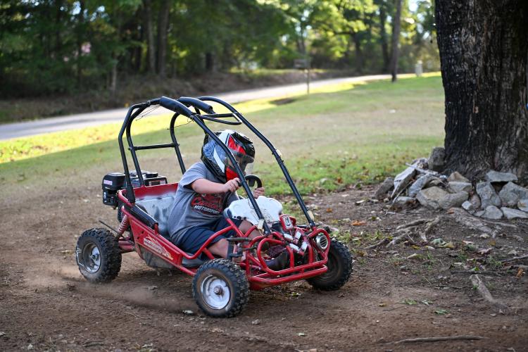 Carson Epps, a 6-year-old OCES student, turns the corner in his go-kart on his family’s front-yard dirt track earlier this month. Caleb, his dad, works on the go-kart during the week for weekend races (Photo/Will Hearn).