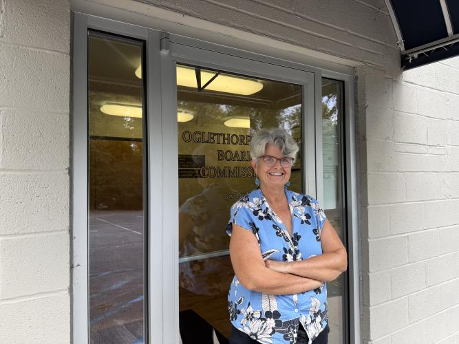 Hill stands and poses in front of the entrance to the zoning board meeting room on Oct. 2, 2026. She is retiring at the end of the year after ten years of service in Oglethorpe County. (Photo/Ren Grimsley)