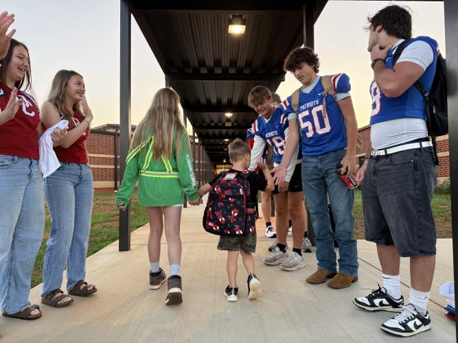 An OCES student high-fives OCHS football player Lance Ellefson as another OCES student guides him through the Patriot Pride drop-off line. “When it started, we figured, let’s just have this amount of players come out, this amount of cheerleaders come out. Now it’s more that they all want to be a part of it,” said athletic booster club president Janine Campbell about the growing popularity of the Patriot Pride Drop-off.