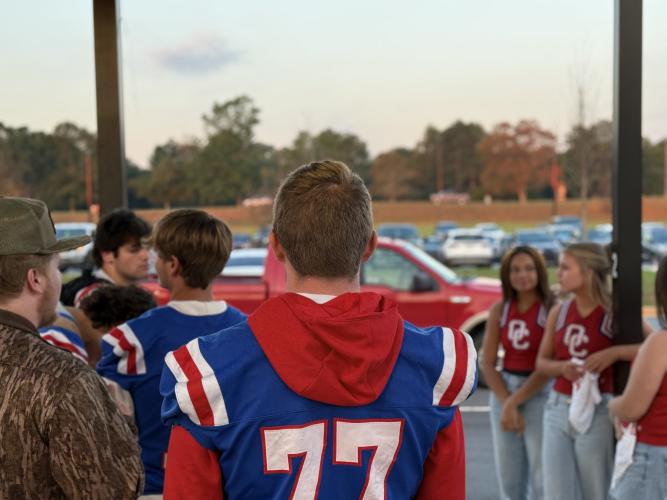 OCHS football player Jake Huff looks out towards the drop-off line at OCES.  ”It humbles them, said Campbell, about what the greeting has had on the players themselves. “It makes them see that they are the leaders for the younger ones, so that carries some weight with them, and makes them realize that you know, they have to do better; they have to be better for the little ones that are always watching them.” (Photo/Walker Durham)