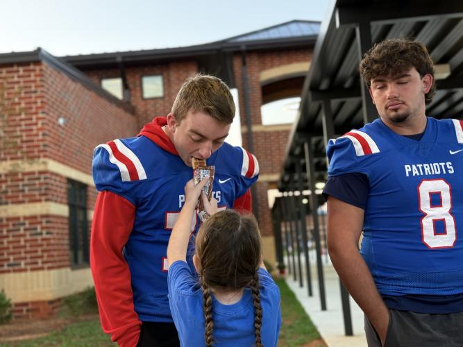 OCHS football player Jake Huff bites into his little sister Emmie Kay's breakfast at the Patriot Pride Drop-off line last Friday morning. The weekly greeting brings together Oglethorpe County students of all ages, even those in the same family.