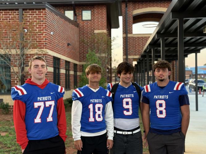 OCHS Football players Jake Huff, Justin Wilson, Coleton Sexton and Brett Liedberg pose beside the Patriot Pride Drop-off line. The players are allowed to miss the beginning of school due to their first class period being taught by Mike Campbell himself.  (Photo/Walker Durham)
