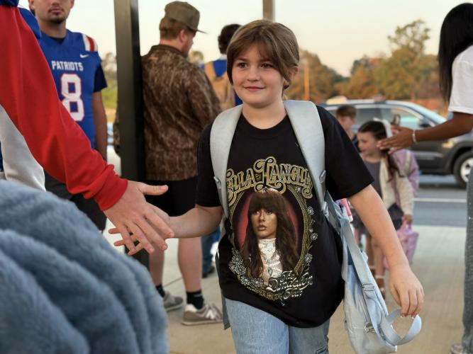 Maggie Blumenshine, an OCES student wearing an Ella Langley shirt, high-fives OCHS football player Jake Huff at the Patriot Pride Drop-Off last Friday. The tradition existed in the past, according to athletic booster club president Janine Campbell, but it wasn’t until this football season that the team decided to bring the tradition back.