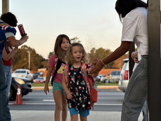 OCES students Jennifer and Caitlyn Bond greet an OCHS cheerleader. “I love it,” said cheerleader Nevaeh Calhoun. “It’s like giving back to the community, because if I was their age when I was little, and I saw cheerleaders and football players want to give me a high-five, I’d probably think I was the coolest person ever.”