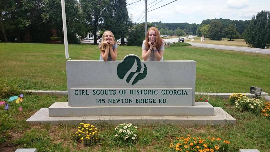 Ansley Land (right) and sister Carrie Tweedell stand behind a sign at the Girl Scouts of Historic Georgia office in Athens when they were younger. Land now works in the office as the membership manager for two service units in the Athens area and Northeast Georgia. (Submitted Photo)