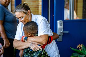 Sandra Wheeler, the bookkeeper and registrar at Oglethorpe County Primary School, hugs a student as children head back to school on Tuesday. (Photo/Jack Casey)